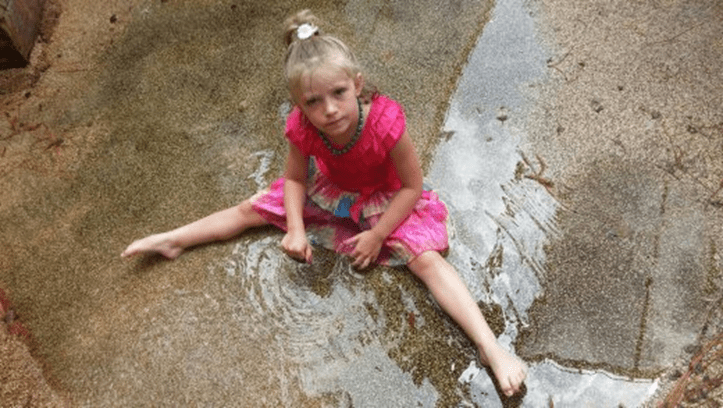 A little girl plays in a puddle and imagines