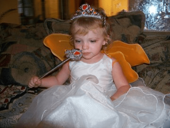 A little girl dressed like a fairy using her imagination